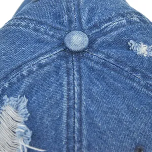Close-up of distressed denim baseball cap showing fabric texture and crown button detail
