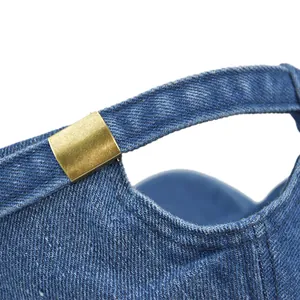 Detail of vintage blue denim baseball cap showing adjustable brass buckle and washed texture