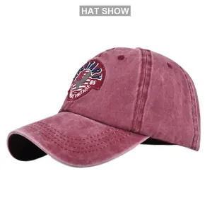 Detail view of burgundy vintage baseball cap with military embroidery and washed cotton texture