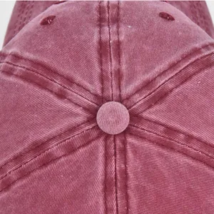Macro shot of distressed deep burgundy cotton fabric with stitching detail on a baseball cap