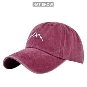 Detailed embroidery of white mountain peaks on washed burgundy vintage baseball cap fabric