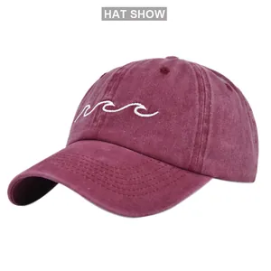 Close-up of wave embroidery and washed cotton texture on a vintage burgundy baseball cap