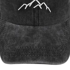Close-up of white mountain peak embroidery on washed black distressed baseball cap
