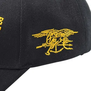 Detail of the golden Navy SEALs trident embroidery on a black tactical baseball cap