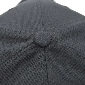 Macro detail of high-density cotton twill fabric and crown button on a black tactical cap