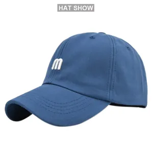 Détail de la broderie M blanche sur une casquette de baseball en coton bleu avec aérations