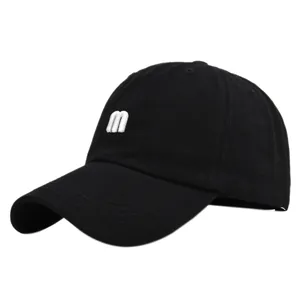 Détail de la broderie lettre m blanche sur une casquette de baseball noire en coton à visière