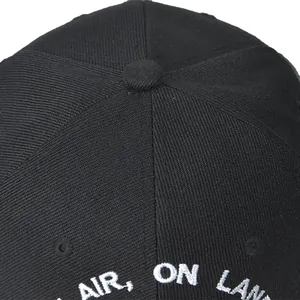 Detail view of the crown button and white AIR ON LAN embroidery on a black baseball cap