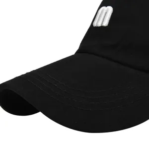 Détail de la lettre M brodée en blanc sur une casquette noire avec coutures sur la visière