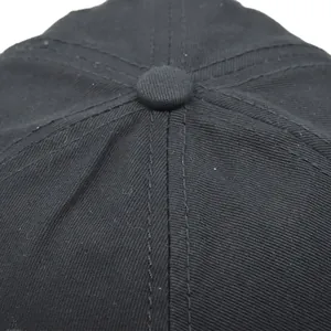 Detailopname van de bovenste knoop en stiksels van een zwarte katoenen baseballpet