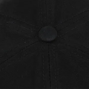 Vista macro del botón superior y las costuras reforzadas de la gorra de sarga negra