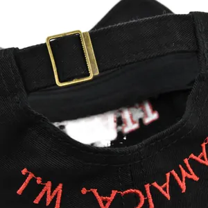 Detalle de hebilla de bronce ajustable y bordado rojo de Jamaica en gorra de algodón negro