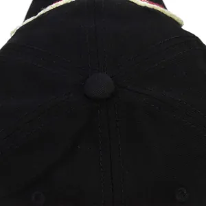 Close-up of the black cotton baseball cap crown with stitched panels and a top button