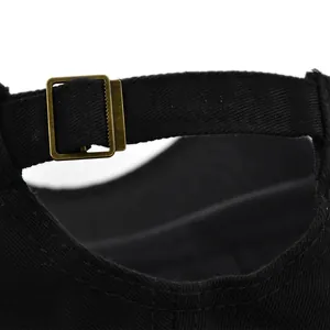 Detail of black baseball cap with adjustable strap and vintage bronze metal slide buckle