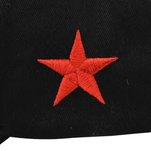 Macro detail of red star embroidery on black cotton twill fabric with dense stitching