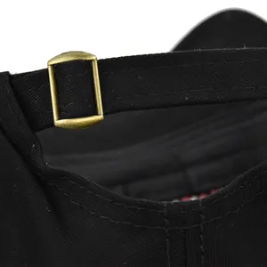 Detail view of adjustable strap with bronze metal buckle on black baseball cap