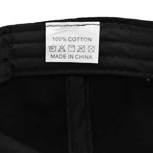 Detailed close-up of 100% cotton washing label inside the black baseball cap