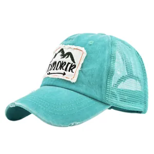 Dettaglio del cappello trucker in mesh verde acqua con patch Explorer e visiera logora