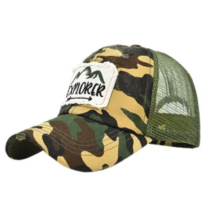 Dettaglio del cappello trucker mimetico con patch EXPLORER e visiera con effetto usurato