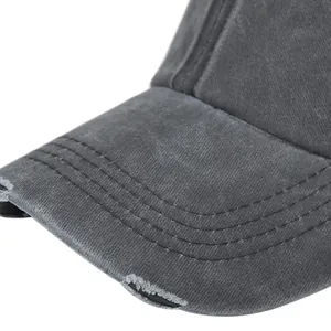 Close-up of distressed brim on dark grey washed cotton ponytail baseball cap with triple stitching