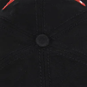 Dettaglio macro del bottone superiore e delle cuciture su un cappellino in cotone nero