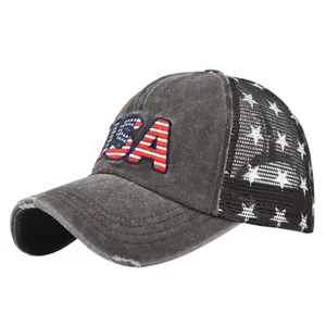 Detail of distressed brim and USA flag embroidery on a grey mesh trucker baseball cap