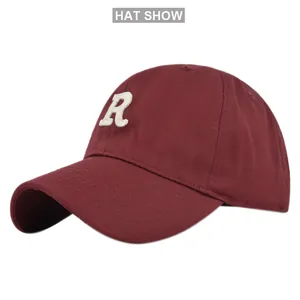 Detailed close-up of white R letter embroidery on dark red baseball cap with cotton texture