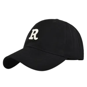 Close-up of premium white R letter embroidery on black cotton baseball cap fabric