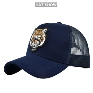 Detail of navy blue trucker hat showing embroidered tiger patch and breathable mesh back