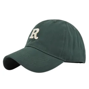 Close-up of white R letter embroidery on dark green cotton twill baseball cap
