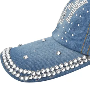Close-up of rhinestone detailing on light blue denim baseball cap with yellow stitching