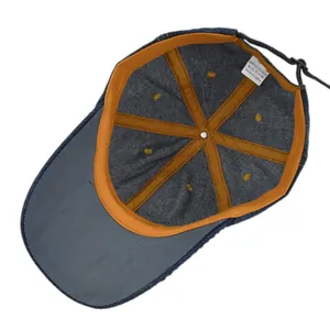 Internal detail of denim baseball cap showing reinforced seams and 100% cotton label