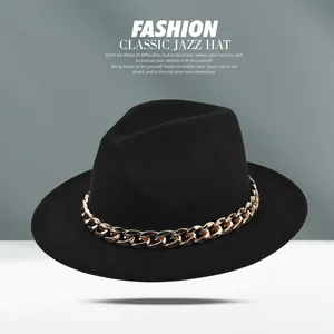 Dettaglio del cappello fedora nero con una grossa catena in metallo dorato sulla tesa larga