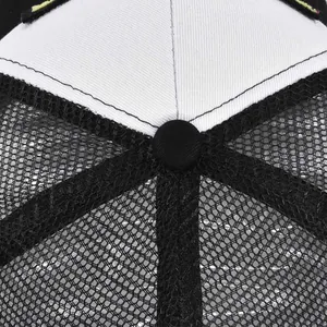 Close-up of black mesh fabric and white cotton panels on a breathable trucker hat