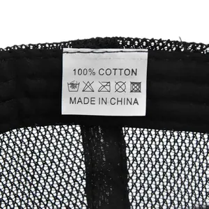 Detailed close-up of 100% cotton fabric wash label inside a black mesh baseball cap