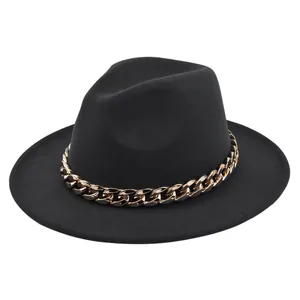 Dettaglio di un cappello jazz in feltro nero con una vistosa catena d'oro audace