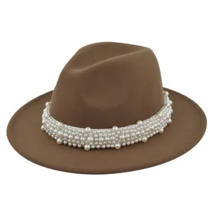 Détail d'un chapeau fedora en laine marron orné de perles blanches sur le ruban
