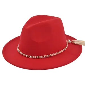Detail shot of the red felt fedora featuring a gold chain with pearls and white tassel