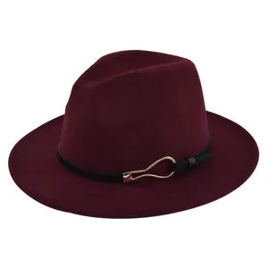 Macro detail of burgundy wool fedora hat featuring black leather band and gold buckle