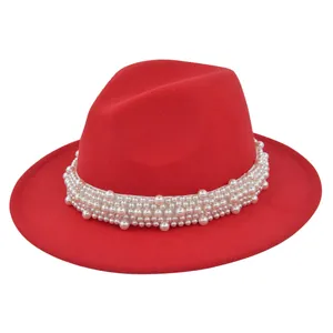 Détail du chapeau fedora en laine rouge avec élégantes perles blanches sur le rebord