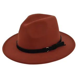 Close-up of rust red fedora hat with black leather band and gold metal ring detail