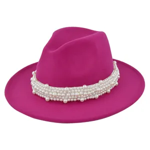 Détail du chapeau fedora rose fuchsia avec un ruban blanc orné de perles élégantes