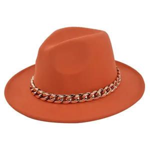 Dettaglio di cappello fedora arancione con spessa catena dorata e tesa piatta in lana