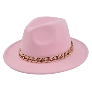 Dettaglio di un cappello fedora in lana rosa con una grossa catena color oro rosa