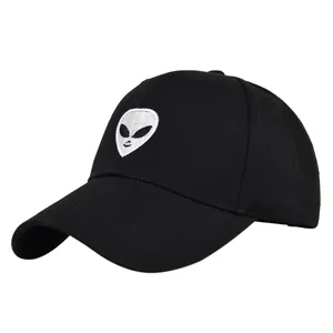 Detailed close-up of white alien head embroidery on a black cotton baseball cap