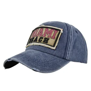 Detail van distressed denim baseballpet met MIAMI BEACH-patch en gerafelde randen