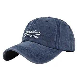 Detailed close-up of white logo embroidery on vintage washed navy cotton baseball cap