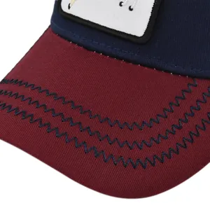 Detail of red visor with blue wavy stitching on a navy blue mesh baseball cap