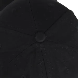 Top-down macro view of black cotton baseball cap showing button and stitched panels