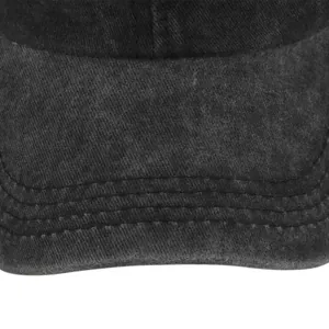 Detail of washed black cotton fabric and reinforced stitching on the baseball cap brim